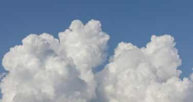 Fluffy white cumulus clouds against a clear blue sky.