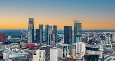 Skyline of a modern city with tall skyscrapers under a clear sunset sky.