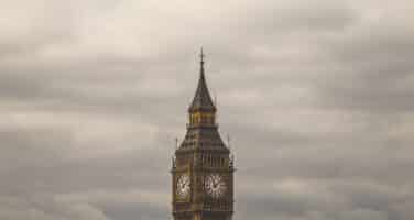 Clock tower against a cloudy sky, with its iconic clock faces visible.