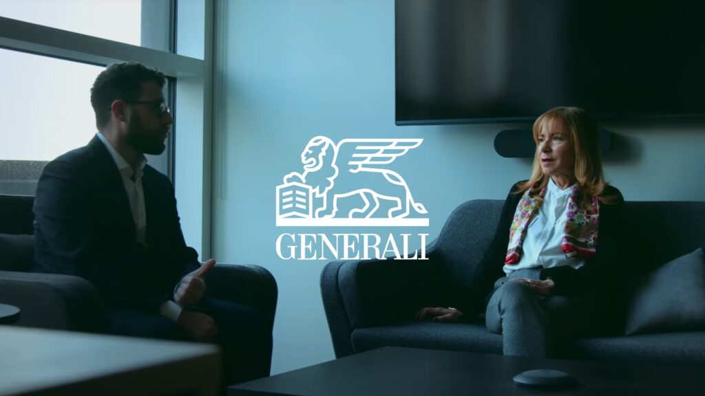 Two people sit in a modern office, engaged in conversation. The Generali logo is superimposed over the image.