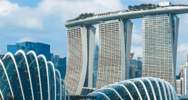 Singapore skyline featuring Marina Bay Sands, with futuristic architecture and towering buildings, under a blue sky.