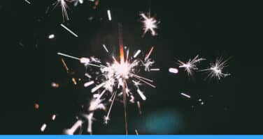 A bright sparkler emitting vivid, sparkling light against a dark background, creating a festive atmosphere.