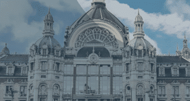 Ornate historic building with a central dome and detailed architectural features against a partly cloudy sky.
