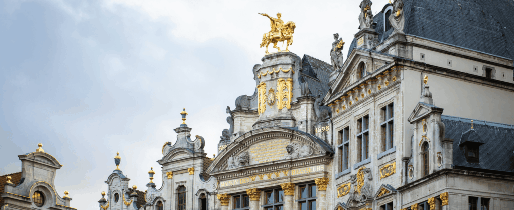 Ornate building facade with detailed architecture, featuring a golden statue of a rider on horseback atop the structure.