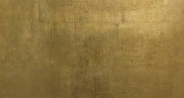 Textured golden surface with a subtle metallic sheen and irregular patterns.
