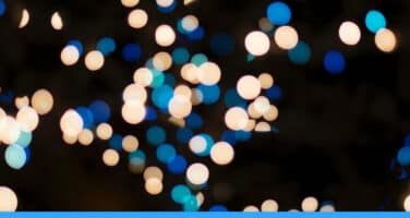 Blurred lights in blue and white create a bokeh effect against a dark background.