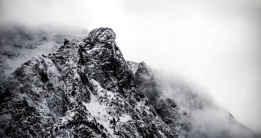 Snow-covered mountain peak shrouded in mist, creating a dramatic and mysterious atmosphere.