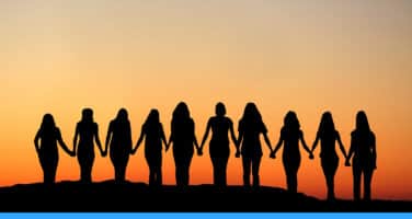 Silhouettes of ten people holding hands, standing against a vibrant orange sunset sky.