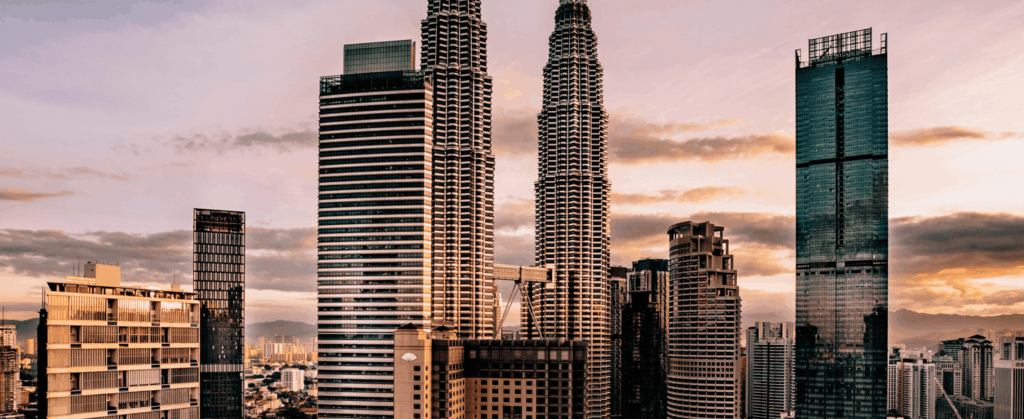 City skyline at sunset with tall skyscrapers silhouetted against a colorful sky.
