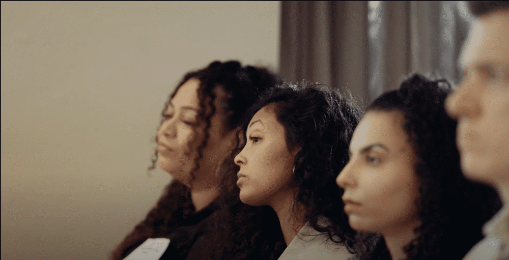 A group of four people sit attentively in a row during a discussion or meeting, focused and engaged.
