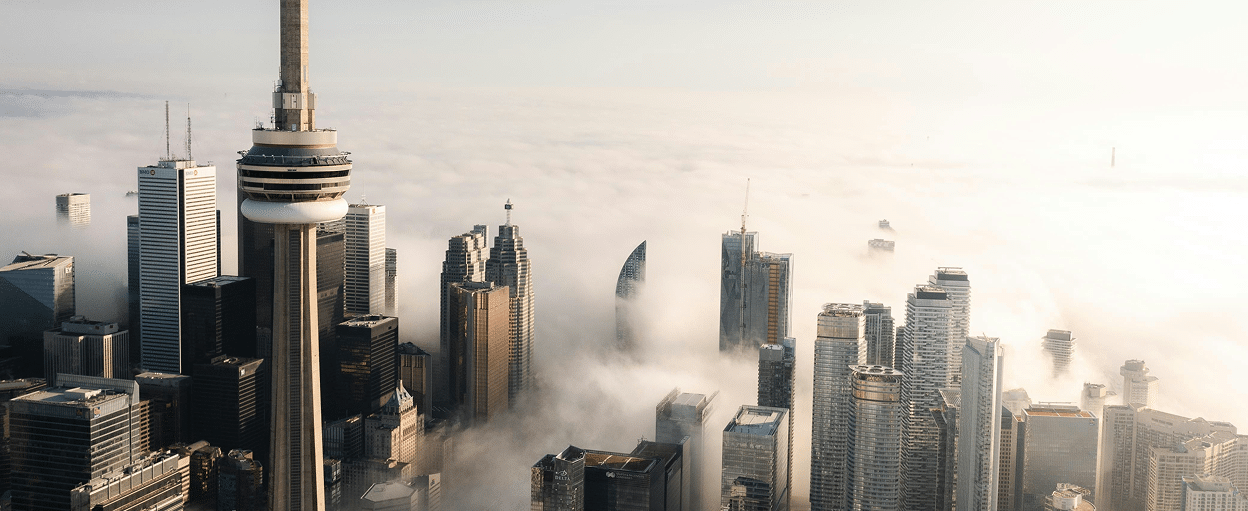 Aerial view of a city skyline with skyscrapers protruding through dense fog, highlighting a prominent tower.